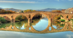 Bridge To The Exit Of Puente La Reina Over A River In A Sunny Day