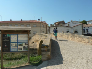 A pilgrim passing through a stone bridge in Lorca