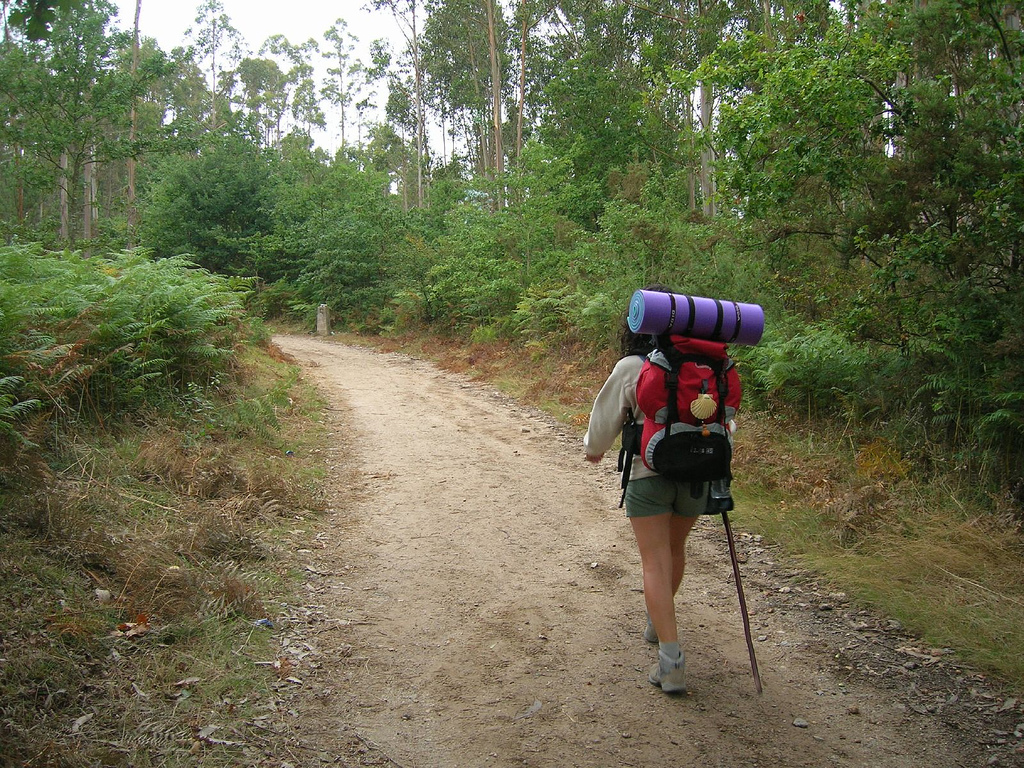 Camino de tierra con una peregrina caminando antes de llegar a Lavacolla